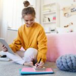 dziecko szkolne rysujące przy biurku z napiętą miną i zmarszczonym czołem