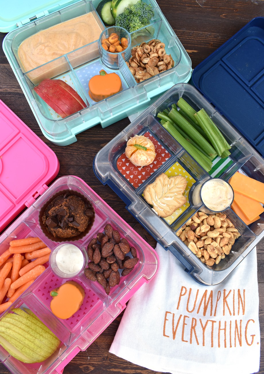 dziecko gryzie czerwone jabłko siedząc przy stole z kolegami