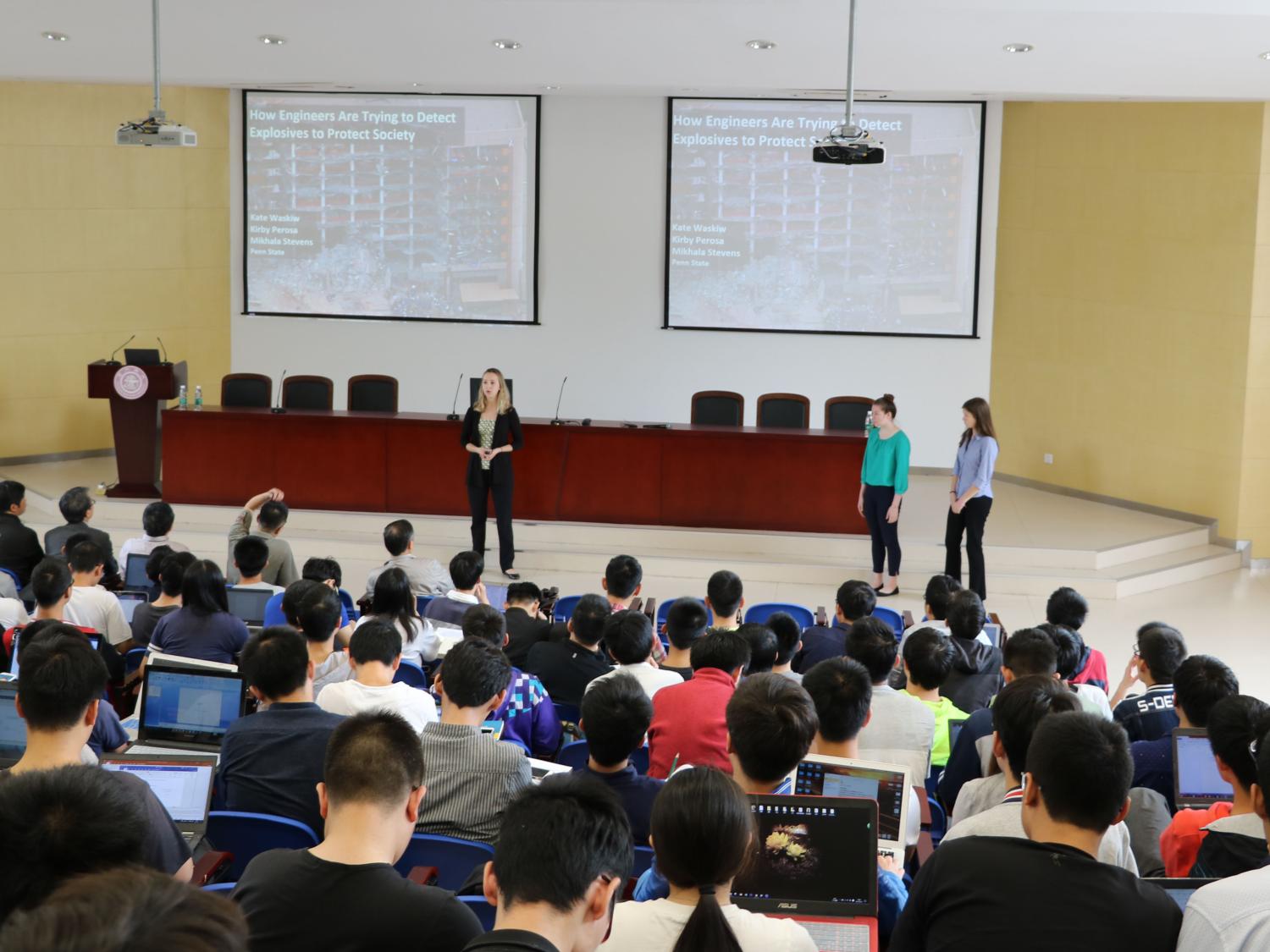 Nauczyciel trzyma tablet z otwartym slajdem i gestykuluje do klasy