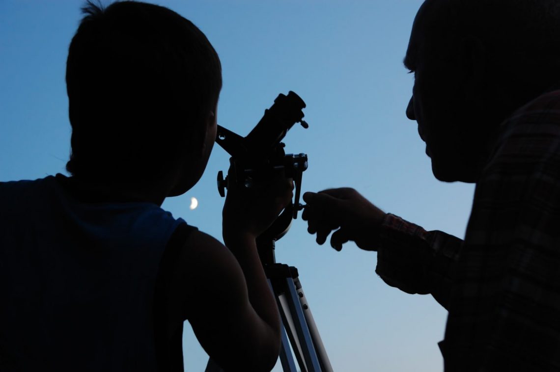 dziecko odkrywa tajemnice nieba dziecko obserwujące księżyc przez teleskop ustawiony na patio
