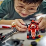dziecko siedzące na podłodze i trzymające model lego technic