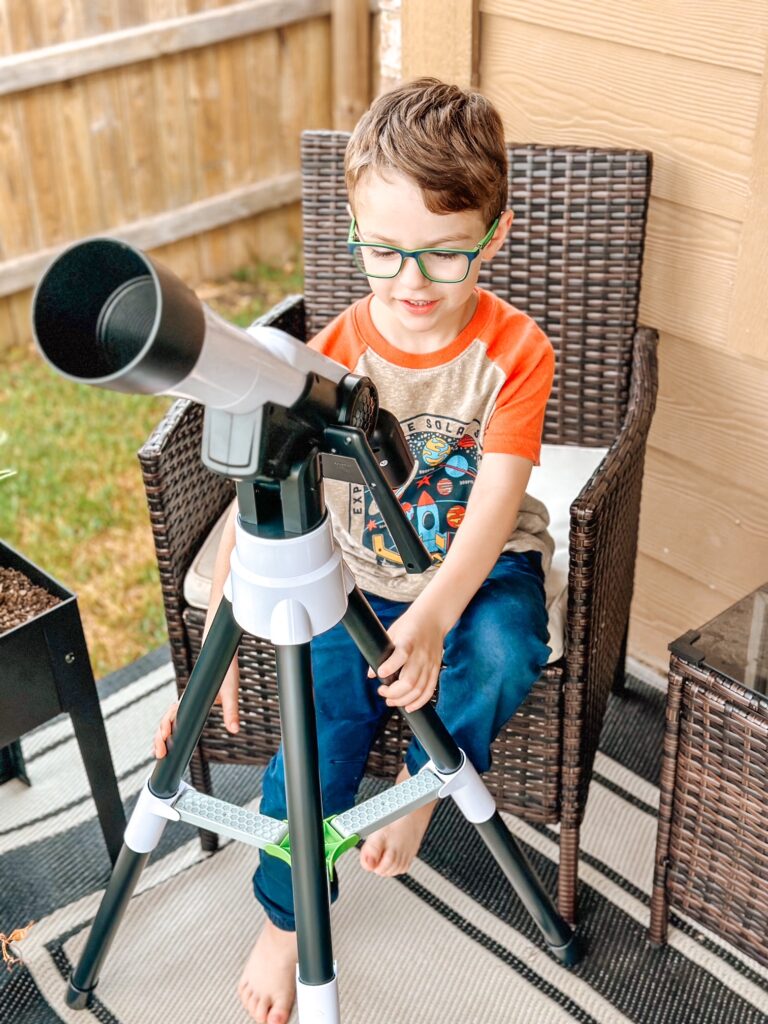 pierwsza lekcja astronomii uczeń szkoły podstawowej czyta instrukcję teleskopu z uśmiechem