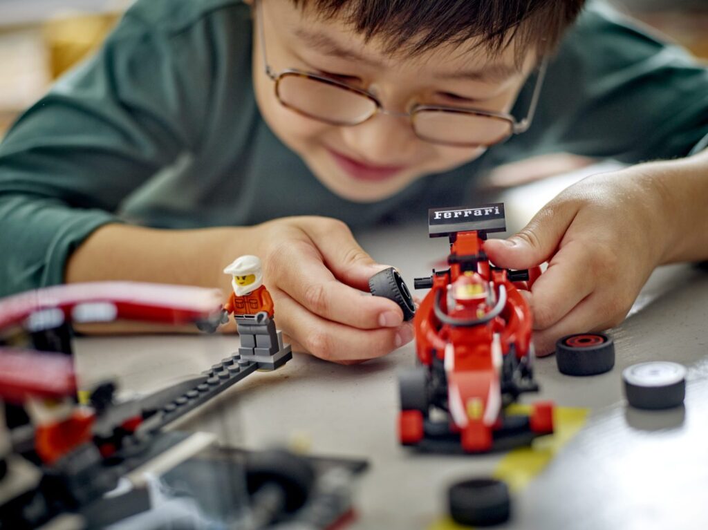dziecko siedzące na podłodze i trzymające model lego technic