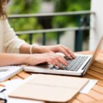 Otwarty notatnik, laptop i materiały do pisania pracy dyplomowej