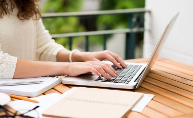Otwarty notatnik, laptop i materiały do pisania pracy dyplomowej