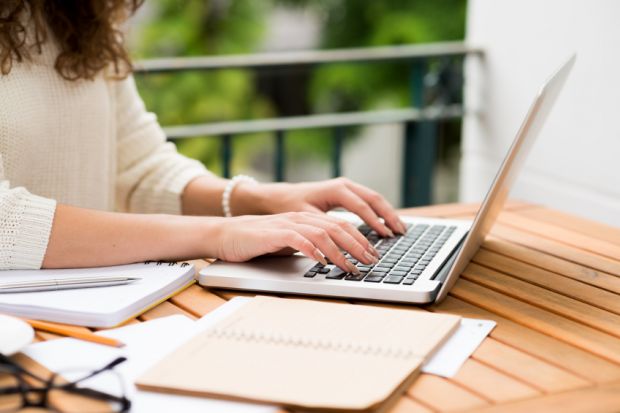 Otwarty notatnik, laptop i materiały do pisania pracy dyplomowej